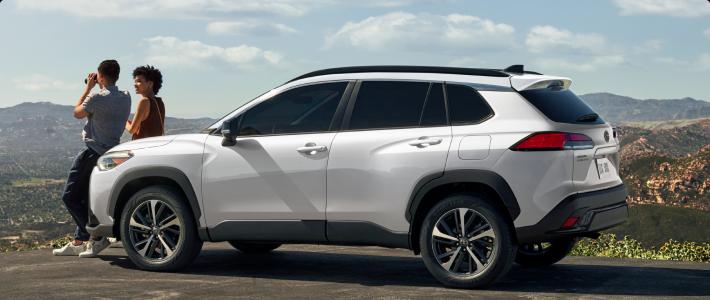 Couple sitting on hood of white Corolla Cross