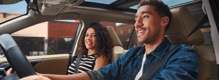 Couple smiling in car while man drives vehicle