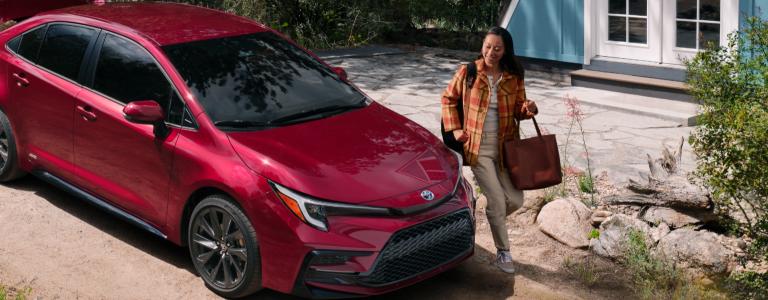 Woman smiling while standing next to Corolla